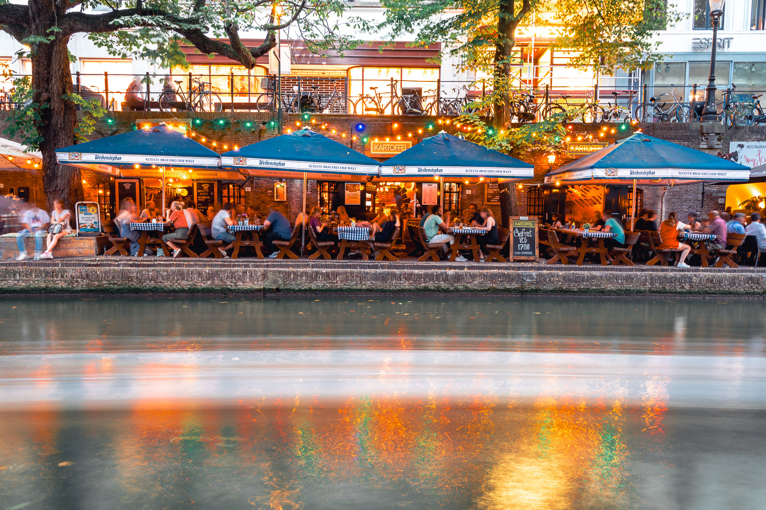 the busy canal side in Utrecht lined with restaurants and people. 